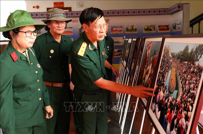Cựu chiến binh xem các tác phẩm nhiếp ảnh được trưng bày. Ảnh: Trung Kiên - TTXVN