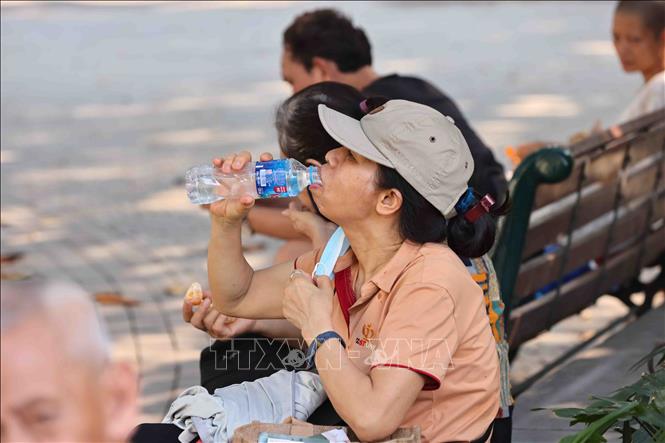 Ra đường những lúc nắng nóng, người dân đều không quên mang theo nước uống. Ảnh: Minh Đức - TTXVN